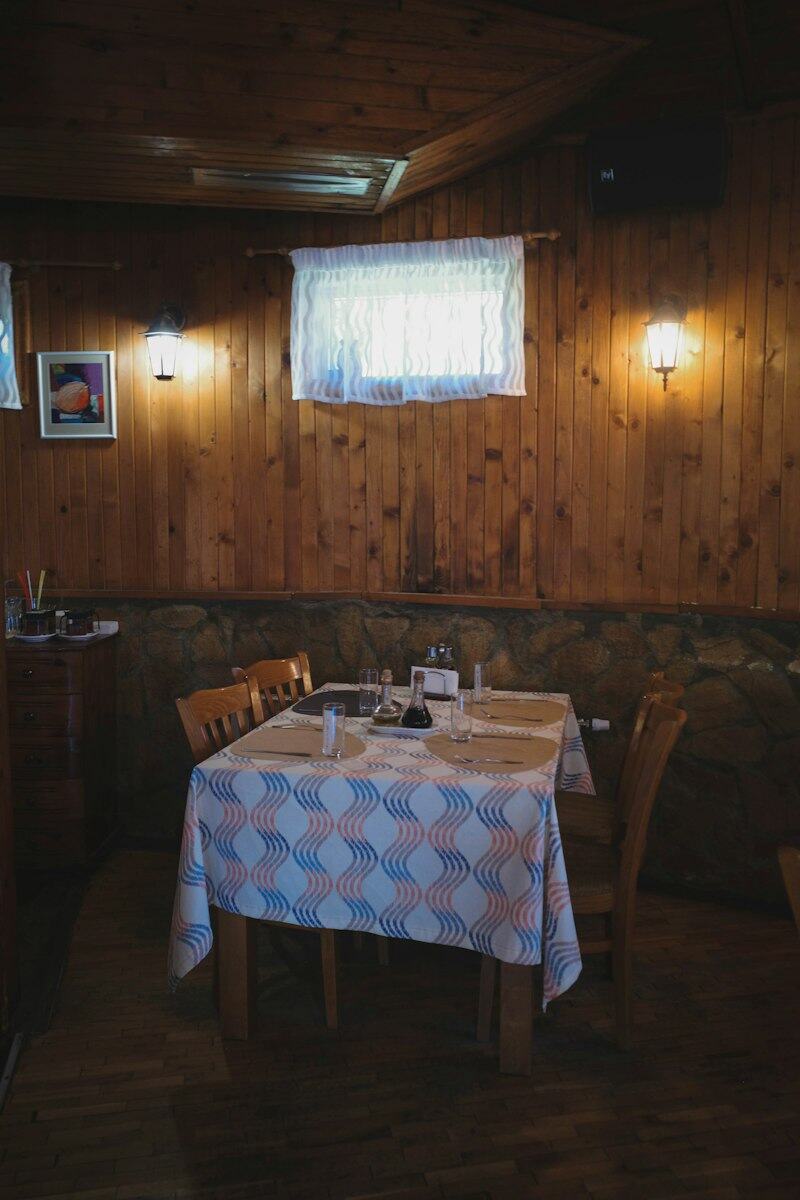 Sala do restaurante com mesa posta e paredes de madeira